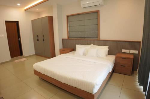 a bedroom with a large bed with white sheets at Faj Platina in Malappuram