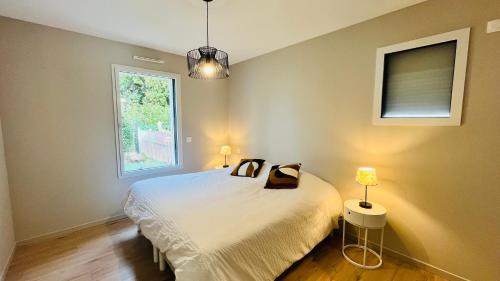 une chambre avec un lit avec deux lampes et une fenêtre dans l'établissement La Garenne, piscine et pinède, à Saint-Jean-de-Monts