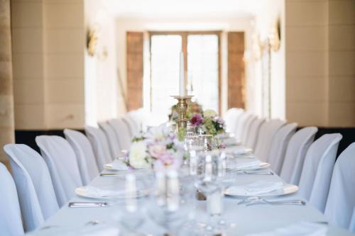 a long table with white chairs and flowers on it at Le Pavillon Saint Martin in Senlis