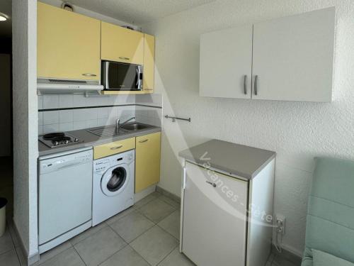 une cuisine avec un lave-linge et un micro-ondes dans l'établissement Studio vue mer avec parking, à Sète