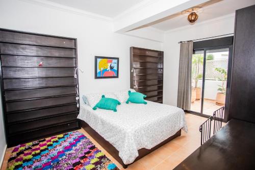 a bedroom with a bed with green pillows on it at Apartamento en Residencia Jardines de Asilah in Asilah