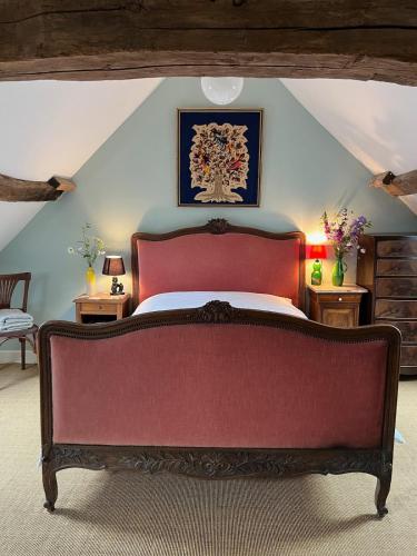 ein Schlafzimmer mit einem roten Bett im Dachgeschoss in der Unterkunft La Petite Bruyere Characterful 2 bedroom cottage with fireplace in Ambrières-le-Grand