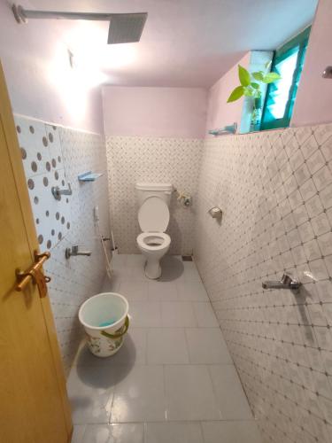 a bathroom with a toilet and a tiled wall at JeeHaa Homestay in Alleppey