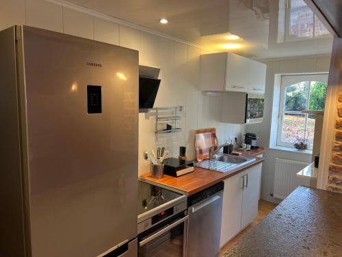 Il comprend une cuisine équipée d'un grand réfrigérateur en acier inoxydable. dans l'établissement Gîte LES GRANDS ARBRES, à Merville