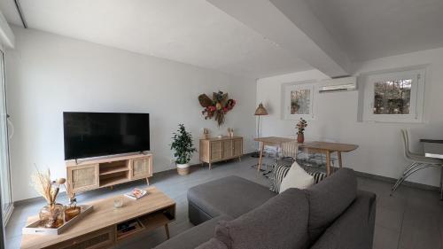 a living room with a couch and a flat screen tv at "LES ALIZES" Côté jardin Proche Bord de mer in Saint-Raphaël
