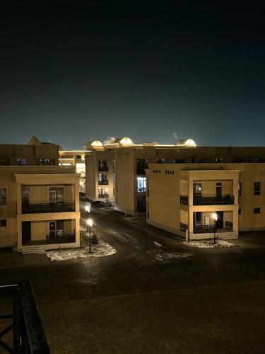 an empty parking lot in front of buildings at night at Sem Brand Hotel in Türkistan