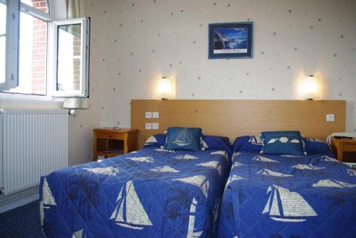 a bedroom with two beds with blue comforters at Hotel Du Parc in Cabourg