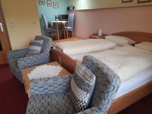 a hotel room with two beds and two chairs at Ferienwohnung In Bayerisch Eisenstein Mit Garten in Bayerisch Eisenstein