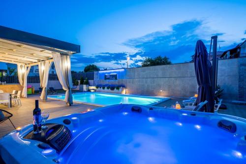 a hot tub on a deck next to a swimming pool at Schöne Villa Beauty Für 6 Personen Und 1 Kind in Brajkovići