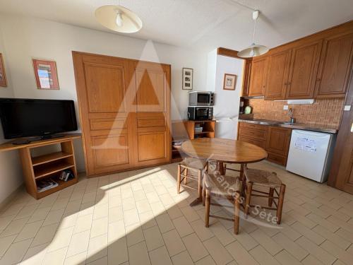 Il comprend une cuisine avec une table en bois et une télévision. dans l'établissement T2 vue mer avec parking et wifi, à Sète