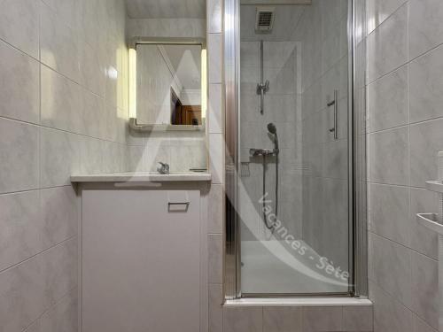 une salle de bain avec une douche, un lavabo et un miroir dans l'établissement T2 vue mer avec parking et wifi, à Sète