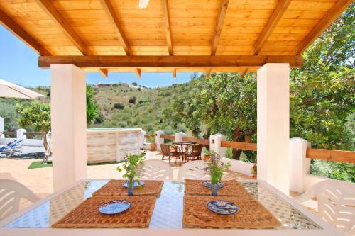 eine Terrasse mit zwei Tischen und einem Holzdach in der Unterkunft Ferienhaus für 6 Personen ca 124 qm in Comares, Andalusien Costa del Sol in Comares