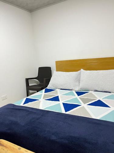 a bedroom with a blue and white bed with a chair at Bogotá Kings 302 in Bogotá