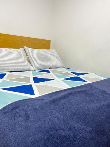a bed with a blue and white comforter and pillows at Bogotá Kings 302 in Bogotá