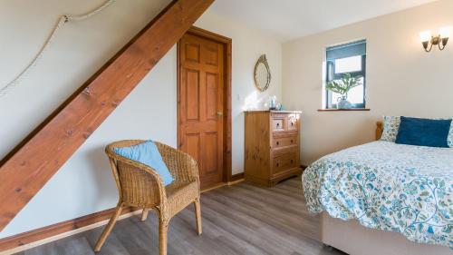 a attic bedroom with a bed and a chair at Moranedd in Llanfaethlu