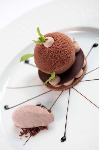 three desserts on a plate on a white table at La Cour des Consuls Hotel & Spa Toulouse - MGallery Collection in Toulouse