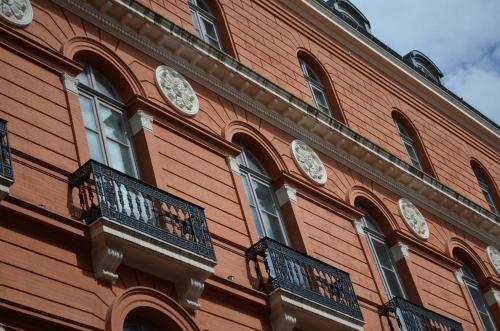 a red building with clocks on the side of it at La Cour des Consuls Hotel & Spa Toulouse - MGallery Collection in Toulouse