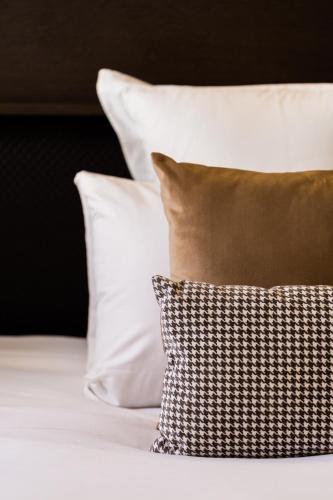 a bed with white pillows and a black and white pillow at La Cour des Consuls Hotel & Spa Toulouse - MGallery Collection in Toulouse