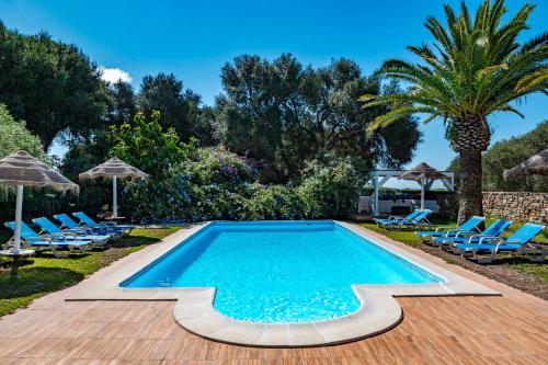 a swimming pool with chairs and a palm tree at Casa Rural Maximón Apartamento Azul in Los Caños de Meca