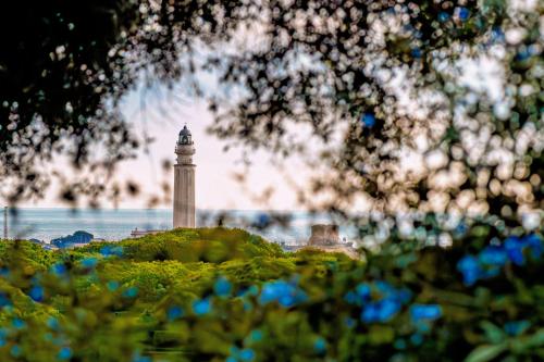 a lighthouse in the middle of the water with blue flowers at Casa Rural Maximón Apartamento Azul in Los Caños de Meca