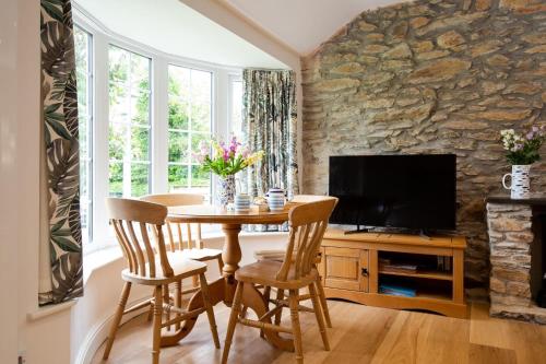 a dining room with a table and a tv at Beautiful Cottage nr Perranporth Private Parking in Perranzabuloe