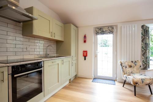 a kitchen with white cabinets and a chair at Beautiful Cottage nr Perranporth Private Parking in Perranzabuloe