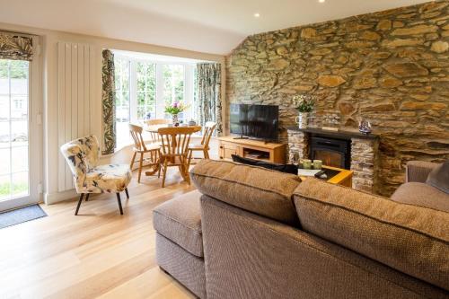a living room with a couch and a stone wall at Beautiful Cottage nr Perranporth Private Parking in Perranzabuloe