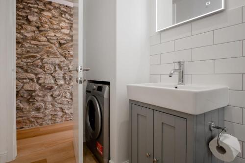 a bathroom with a sink and a washing machine at Beautiful Cottage nr Perranporth Private Parking in Perranzabuloe