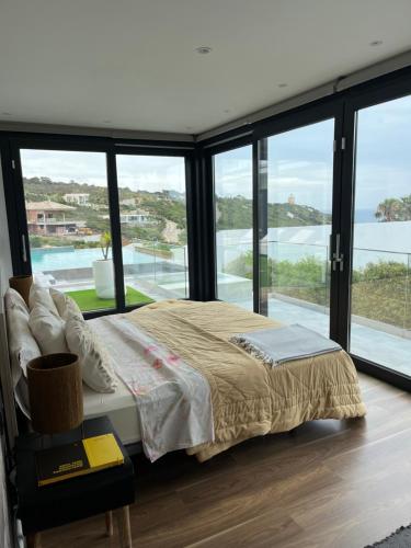 a bedroom with a bed and large glass windows at Villa Essencia in Zahara de los Atunes