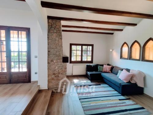 a living room with a blue couch and a stone wall at Villa Paradise in Calonge
