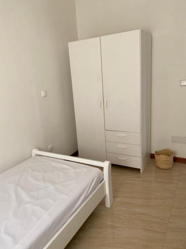 a bedroom with a bed and a white cabinet at Casa Carveiros Panoramic 360 in Tarrafal