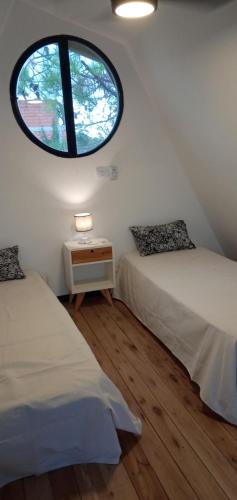 two beds in a room with a large window at Lapachos blco cabañas in Federación