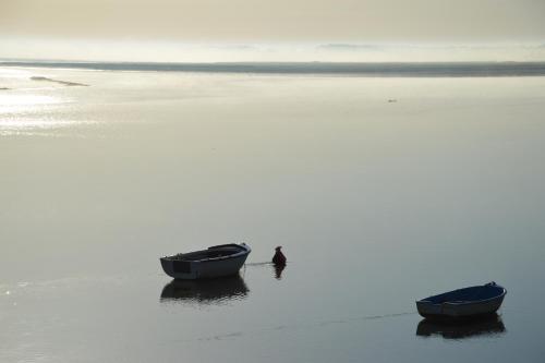 deux bateaux sur une plage avec une personne debout dans l'eau dans l'établissement L'Abricotier, à Saint-Valery-sur-Somme