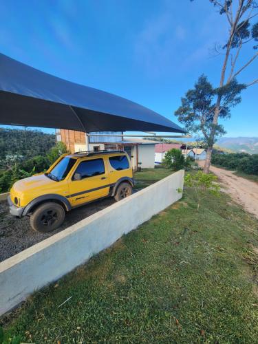 a yellow jeep parked under a blue canopy at Chalé dos Manacás Duplex in Venda Nova do Imigrante
