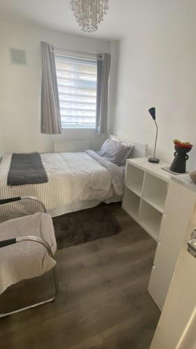 a white bedroom with a bed and a window at Convenient Home-stay in London