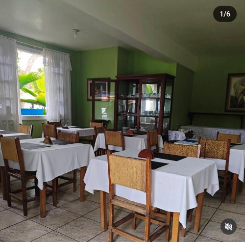 a restaurant with white tables and chairs and green walls at Pousada do Deck in Alcobaça