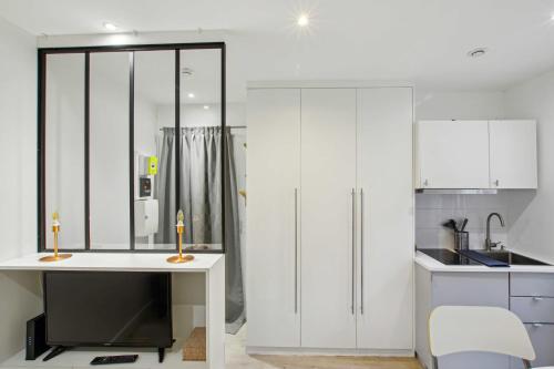 - une cuisine avec des placards blancs et un bureau blanc dans l'établissement Le Petit cosy de Montmartre, à Paris