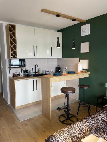 a kitchen with white cabinets and a counter with stools at Check In Apartment Kladovo in Kladovo