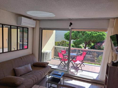 un salon avec un canapé, une table et des chaises dans l'établissement Hélios 32, T2 climatisé, parking, 500m plage, au Cap d'Agde