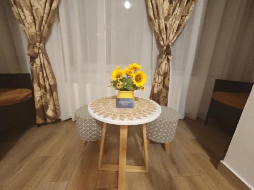 a table with a vase of sunflowers on it at Apartament Luca in Călimăneşti