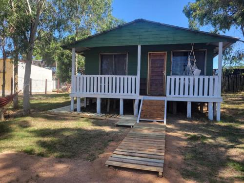 a small green house with a porch and two benches at Ananda Lodge A special haven in Punta Del Diablo