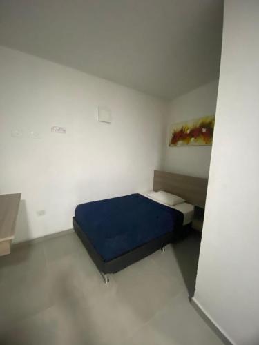 a bedroom with a blue bed in a white room at Hotel America 52 in Rionegro