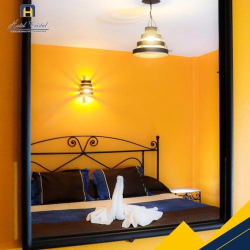 a mirror in a bedroom with a bed and lights at Hotel Cristal Chignahuapan in Chignahuapan