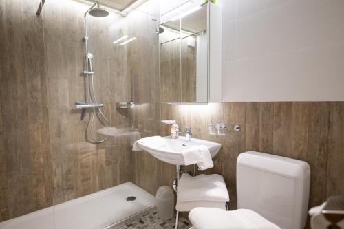 Un baño con lavabo, ducha e inodoro. en Feriensiedlung Trü 7, en Scuol