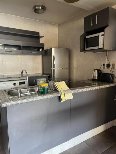 a kitchen with a sink and a microwave at Departamento soleado y acogedor en el mejor barrio de la ciudad in La Paz