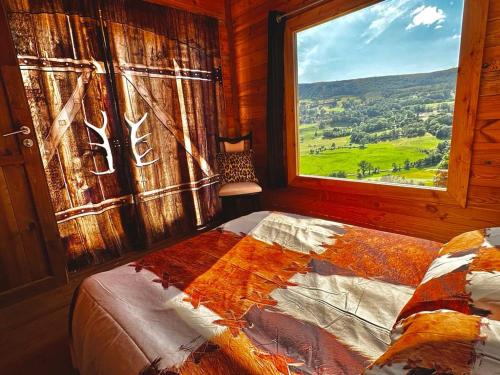 a bedroom with a window and a bed with a view at Cabanes Milvus du Puy Mary in Cheylade