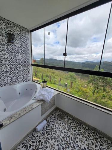 a bathroom with a tub and a large window at La Villa Novas Pousada in Lavras Novas