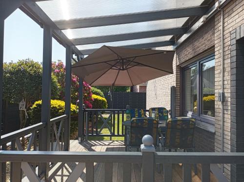 a patio with an umbrella and chairs on a deck at Ferienwohnung Zwei Finken In Wiesmoor in Wiesmoor