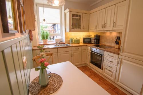 a kitchen with white cabinets and a vase of flowers on a table at Gemütliche Wohnung In Bracht Mit Terrasse Und Garten in Rauschenberg