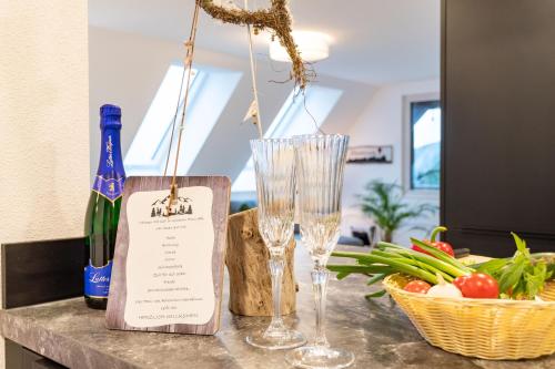 a table with two wine glasses and a basket of vegetables at Fewo Mit Whirlpool Und Fass Sauna Im Schwarzwald in Hausach